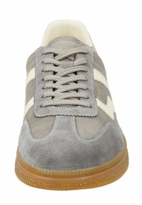 Šedé semišové tenisky s kulatou špičkou, bílými pruhovanými akcenty a gumovou podrážkou s texturovaným detailem. Šněrování s plochými šedými tkaničkami.