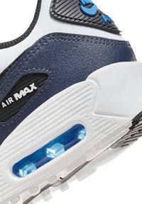 Sneaker Air Max má bílou a námořnickou koženou vrchní část, texturované černé akcenty a modrou viditelnou vzduchovou polstrovanou jednotku na podešvi.