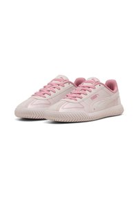 Sneaker rosa chiaro con tomaia liscia, dotate di lacci rosa e suola testurizzata con un motivo a righe. Logo Puma visibile sul lato.