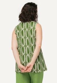 Groene mouwloze top met een geometrisch bladenpatroon in lichtere tinten, met een relaxte pasvorm en ronde hals. De stof lijkt lichtgewicht te zijn.