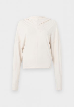 Κρεμ cropped φούτερ με μακριά μανίκια, άνετη εφαρμογή και ελάχιστες ραφές, σε απλό φόντο.