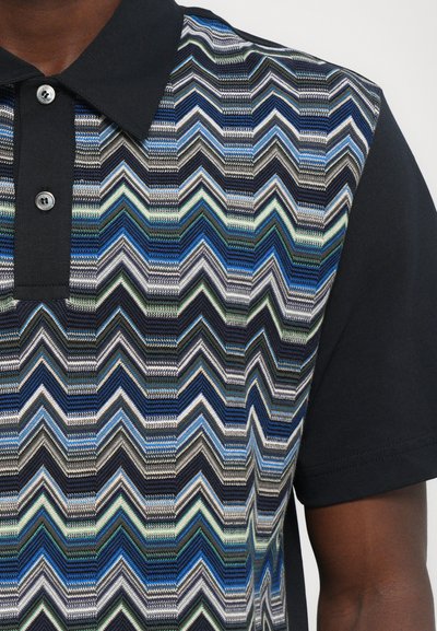 Tricou polo cu guler, prezentând un model geometric în zigzag în nuanțe de albastru, verde și gri pe față, cu mâneci scurte negre și nasturi.