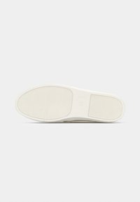 Semelle d'une chaussure blanche avec une accroche texturée et la taille 42 marquée au centre, présentée sur un fond clair uni.