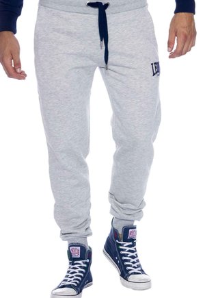 Modèle portant un pantalon de jogging gris clair à cordon de serrage et des baskets montantes bleu marine sur fond blanc.