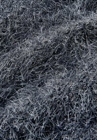 Textured fabric in dark gray with metallic silver strands, featuring a fuzzy appearance and uneven, wavy surface pattern.