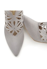 Šedé lodičky s otevřenou špičkou vyrobené z texturovaného semiše s laserovým vyřezáváním květinových vzorů, mírně špičaté špičky a nízkým podpatkem.
