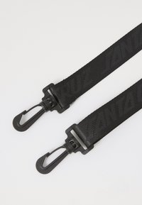 Zwarte nylon strap met een textuur oppervlak en bedrukte branding, met aan elk uiteinde twee haken voor bevestiging.