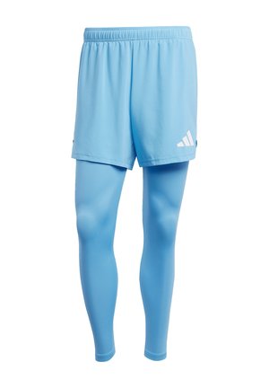 Lichtblauwe sportshorts met een elastische tailleband, gedragen over bijpassende fitted leggings. Voorzien van witte logo-accenten op de shorts.