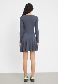 Pitkähihainen, slim fit -mekko tummansinisellä värillä, jossa on liehukehelma. Raidoitettu pinta ja avara selkäosa. Yhdistetty tummansinisiin ja vihreisiin lenkkareihin.