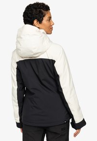 Zwarte en crèmekleurige waterdichte jas met capuchon, voorzien van een kleurblokkenontwerp en een logo-label aan de zoom. Glad textuur en slanke pasvorm.