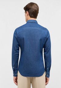 Donkerblauwe langekemshirt gemaakt van denim, met een klassieke kraag, knopenmanchet en een gebogen zoom met subtiele stikdetails.