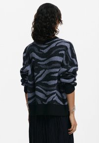 Maglione lavorato a maglia con un motivo a strisce di tigre in nero e viola chiaro, caratterizzato da una vestibilità comoda e polsini e orlo a costine.