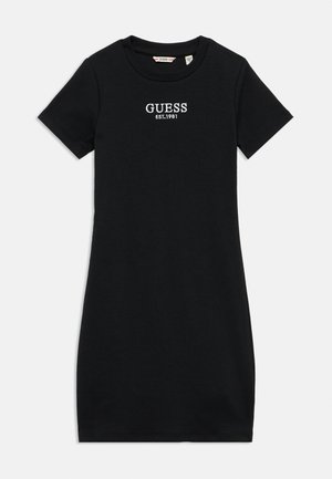 Abito t-shirt nero in cotone con maniche corte, silhouette aderente e logo bianco "GUESS EST.1981" sul petto. Texture liscia, design semplice.