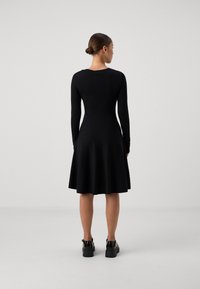 Black long-sleeve dress with a fitted bodice and flared skirt. Made of soft fabric. Features a round neckline and minimal design.