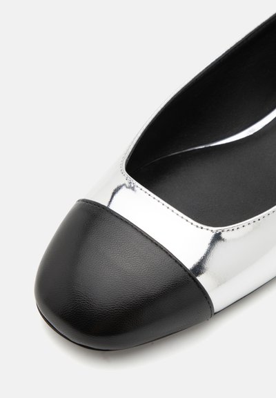 Silberne, metallische flache Schuhe mit einer schwarzen Lederkappe und glattem Innenfutter; verfügen über ein tief ausgeschnittenes Design und eine robuste Sohle.