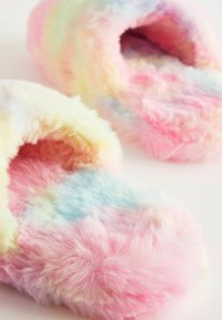 Regnbågsfärgade plyschtofflor med en fluffig textur. Har mjuka pastellfärger i rosa, gult och blått. Rund tådesign.