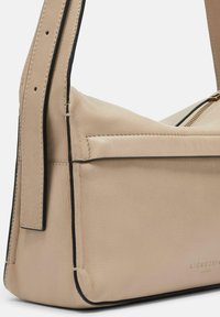 Borsa a spalla in pelle beige chiaro con un design strutturato, rifiniture nere a contrasto e un logo del marchio embossato sul lato. Cerniere visibili.