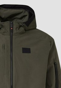 Zaļš kapuci ar melnu rāvējslēdzēju un nelielu melnu taisnstūrveida uzlīmi uz krūtīm, kapucē ir regulējamas aukliņas.