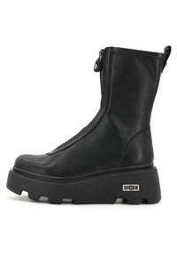 Stivaletti in pelle nera con zip laterale, suola piattaforma chunky e branding discreto sul lato esterno. Texture liscia, design elegante.