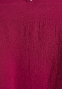 Gros plan sur un tissu froissé de couleur rouge magenta foncé avec une surface texturée.