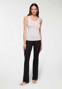 Top in cotone grigio chiaro a maniche corte con scollo a barca, abbinato a pantaloni neri a campana. Entrambi i capi sono realizzati in un tessuto liscio e elasticizzato.