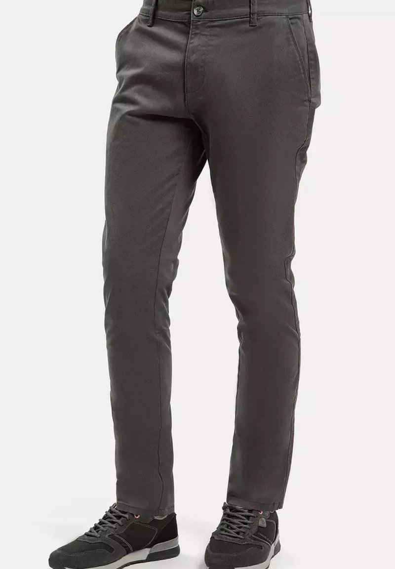 Szare spodnie o prostym kroju, wykonane z gładkiego materiału. Zawierają przednie kieszenie i zapięcie na guzik, zestawione z czarnymi trampkami.