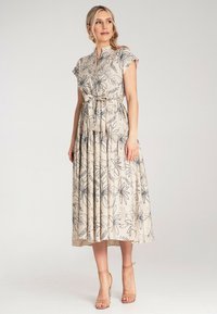 Maxikleid mit floralem Druck aus leichtem beigen Stoff, mit knöpfbarem Ausschnitt, tailliertem Bund und plissiertem Rock. Verstellbares Bindeband in der Taille.