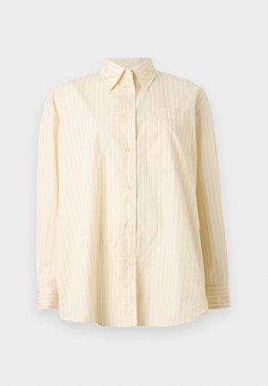 Camisa amarilla clara de manga larga con botones, con rayas verticales blancas y un bolsillo en el pecho, mostrada sobre un fondo blanco liso.