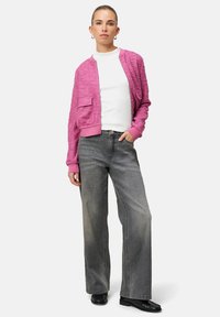Textured pink bomber jacket with ribbed cuffs, worn over a white top and paired with wide-leg gray jeans and black shoes.
