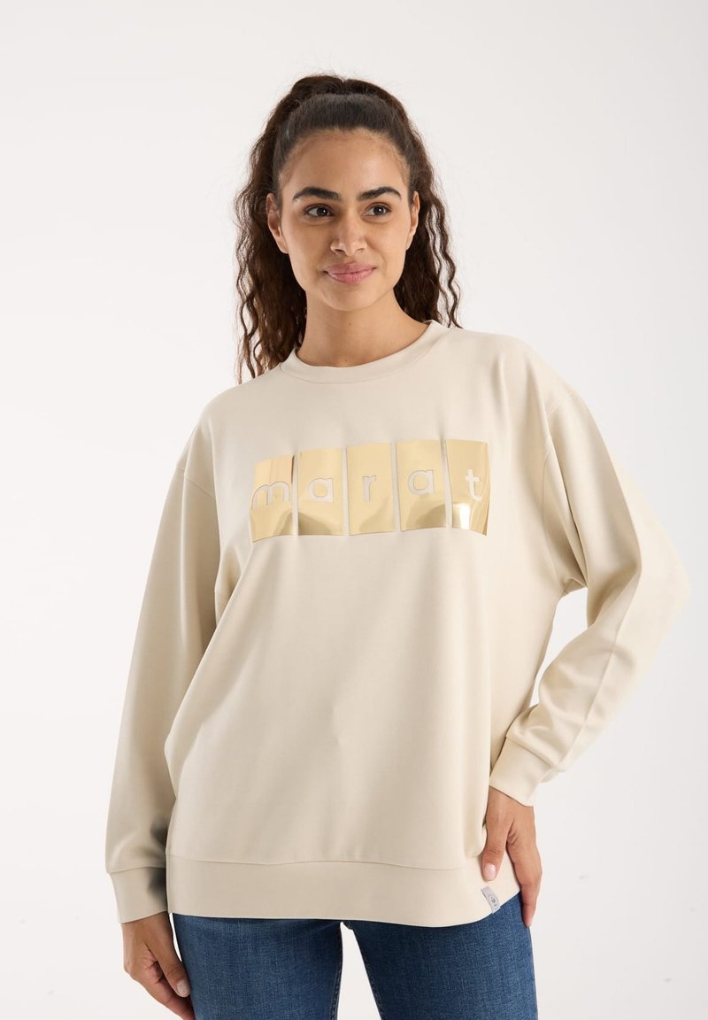 Beżowa bluza z długimi rękawami, z błyszczącą graficzną aplikacją logo w kolorze żółtym. Miękka tkanina o luźnym kroju i ściągaczach.