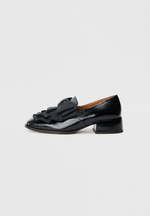 Chaussure en cuir verni noir à bout arrondi, ornée d'un nœud en tissu noir proéminent et d'un petit talon bloc.