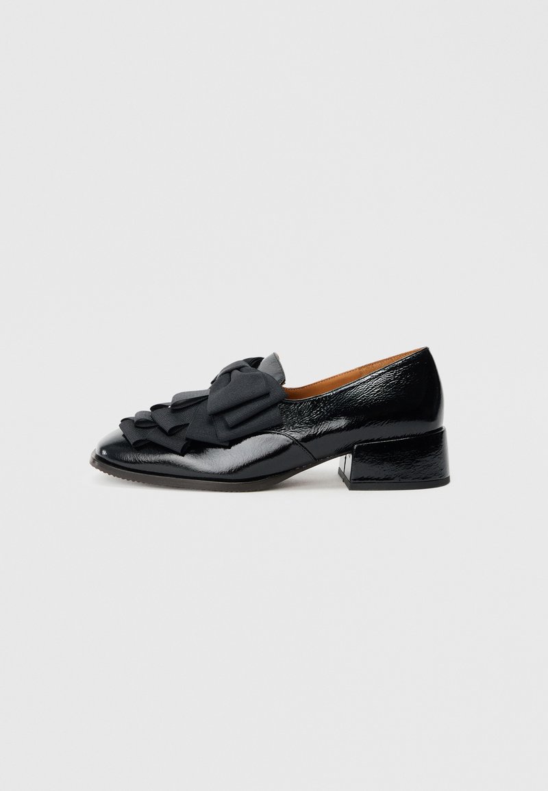 Chaussure en cuir verni noir à bout arrondi, ornée d'un nœud en tissu noir proéminent et d'un petit talon bloc.
