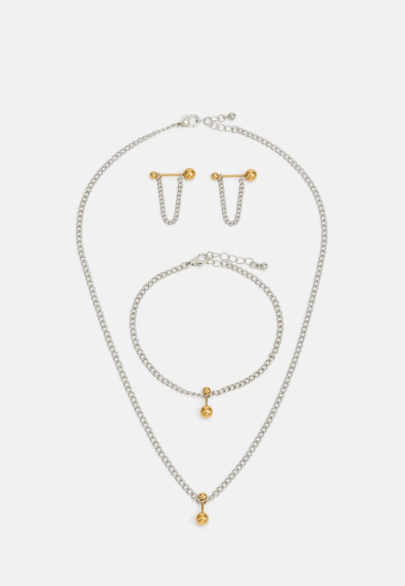 Sølvmetall smykkesett med kjedehalskjede, armbånd og øredobber. Gullkule aksenter på kjedene. Enkel, moderne design.