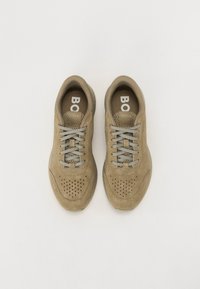 Adidași sport bej din suede, cu un upper texturat, detalii perforate, șireturi gri și o talpă din cauciuc, etichetați "BOSS" pe limbă.