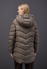 Chaqueta acolchada de color marrón con patrón de Chevron y capucha, que cuenta con bolsillos laterales y un diseño ligeramente más largo en la parte posterior.