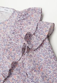 Bluse mit floralem Muster aus hellviolettem und weißem Stoff, mit gerafften Details an den Ärmeln und einer subtilen Textur.