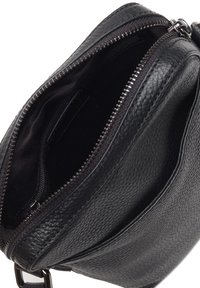 Borsa a tracolla in pelle nera con esterno testurizzato, dotata di chiusura con zip e fodera interna liscia. Tasca interna visibile.