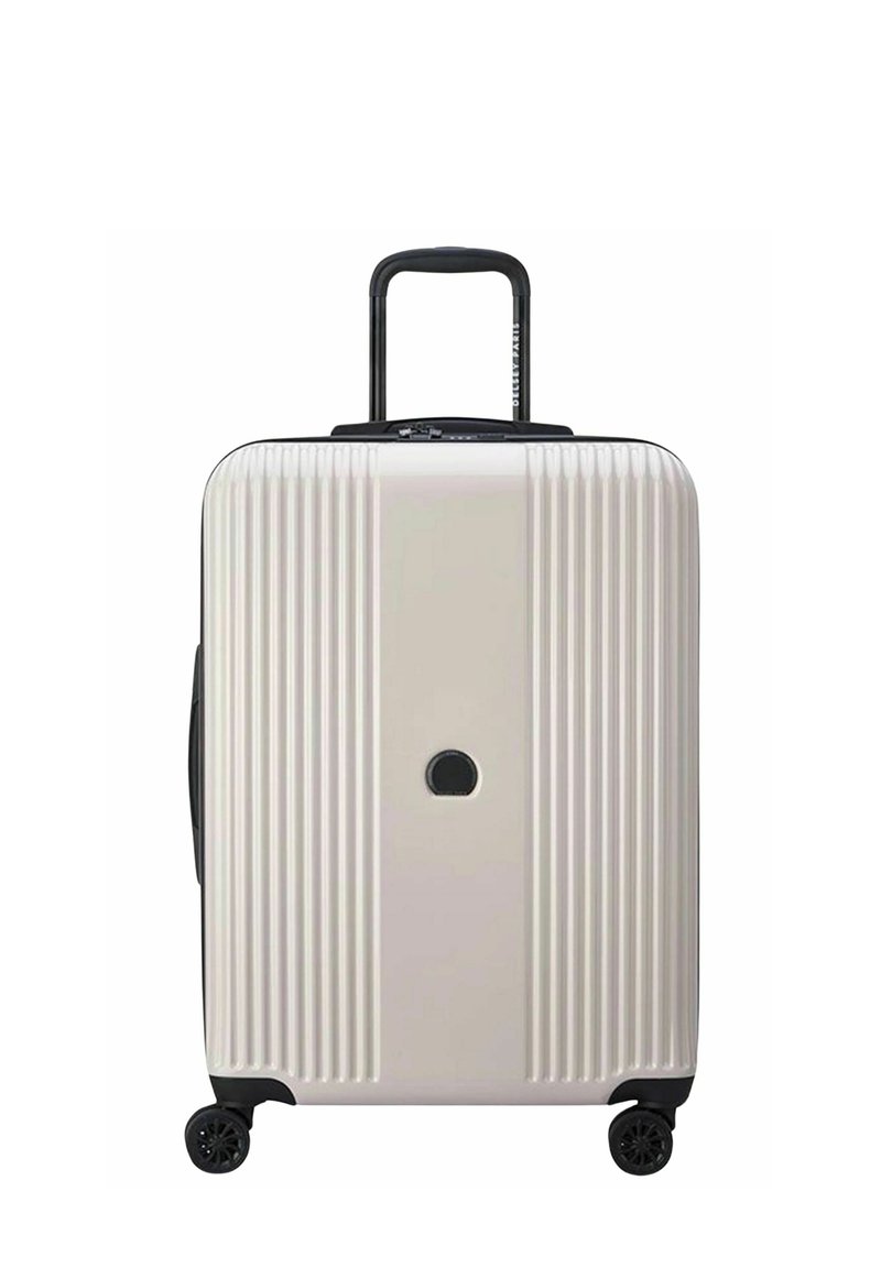 Valigia rigida di colore beige chiaro, con scanalature verticali, manico retrattile nero e quattro ruote nere. Inclusa una serratura circolare.