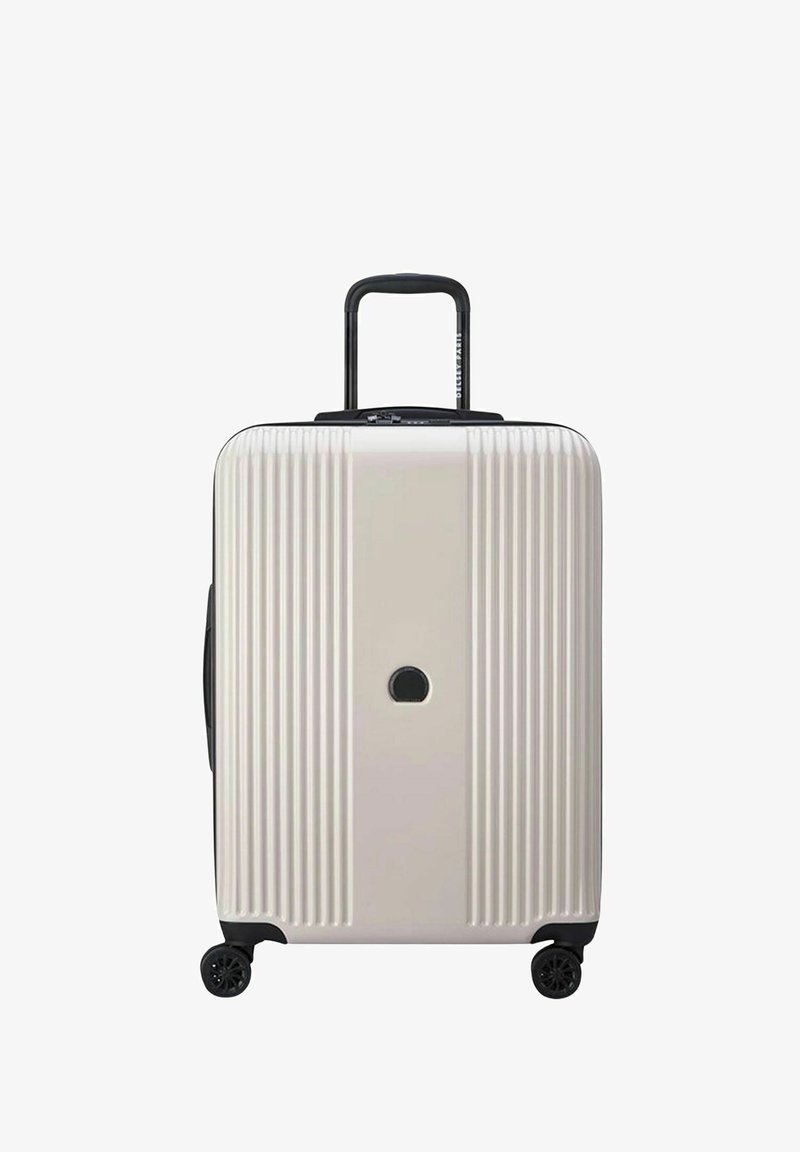 Valigia rigida di colore beige chiaro, con scanalature verticali, manico retrattile nero e quattro ruote nere. Inclusa una serratura circolare.