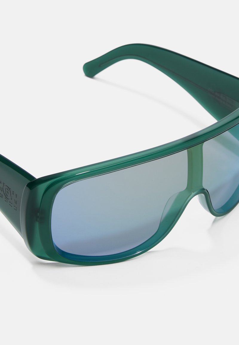 Grüne Plastiksonnenbrille mit einem Wraparound-Design. Hellblaue Verlaufslinsen und glatte Textur. Verfügt über breite Seiten für verbesserten Schutz.