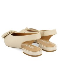 Zapatos slingback beige con detalle de lazo anudado, lados abiertos y suela de goma plana. Material sintético suave y plantillas acolchadas.