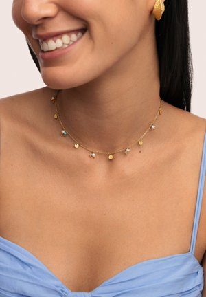 Gouden ketting met kleine kleurrijke bedels en ronde hangers, die een delicate uitstraling heeft met gevarieerde texturen en accenten.