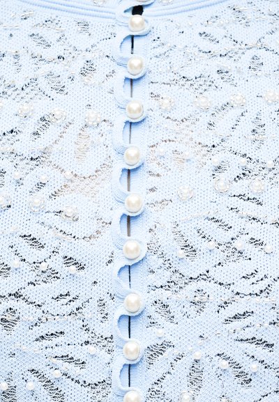 Υφασμα από ανοιχτό γαλάζιο δαντέλα με κουμπιά από μαργαριτάρια και μικρές διακοσμήσεις από μαργαριτάρια και χάντρες σε σχέδια λουλουδιών και στροβιλισμούς.