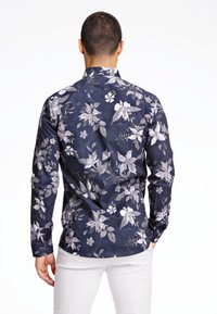 Camicia a maniche lunghe blu navy con grande motivo floreale grigio; tessuto liscio, colletto classico e polsini con bottoni; taglio sartoriale, vista posteriore mostrata.