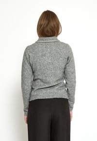 Maglione grigio in lana con colletto ripiegato, superficie textured e una leggera lucentezza dovuta agli accenti metallici vicino allo scollo. Design slim fit.