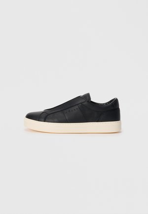 Mustat nahkaiset slip-on-tennarit, joissa on sileä pinta, pyöreä kärki ja beige ulkopohja. Ominaisuuksiin kuuluu minimalistinen muotoilu ja huomaamattomat ompeluaccentsit.