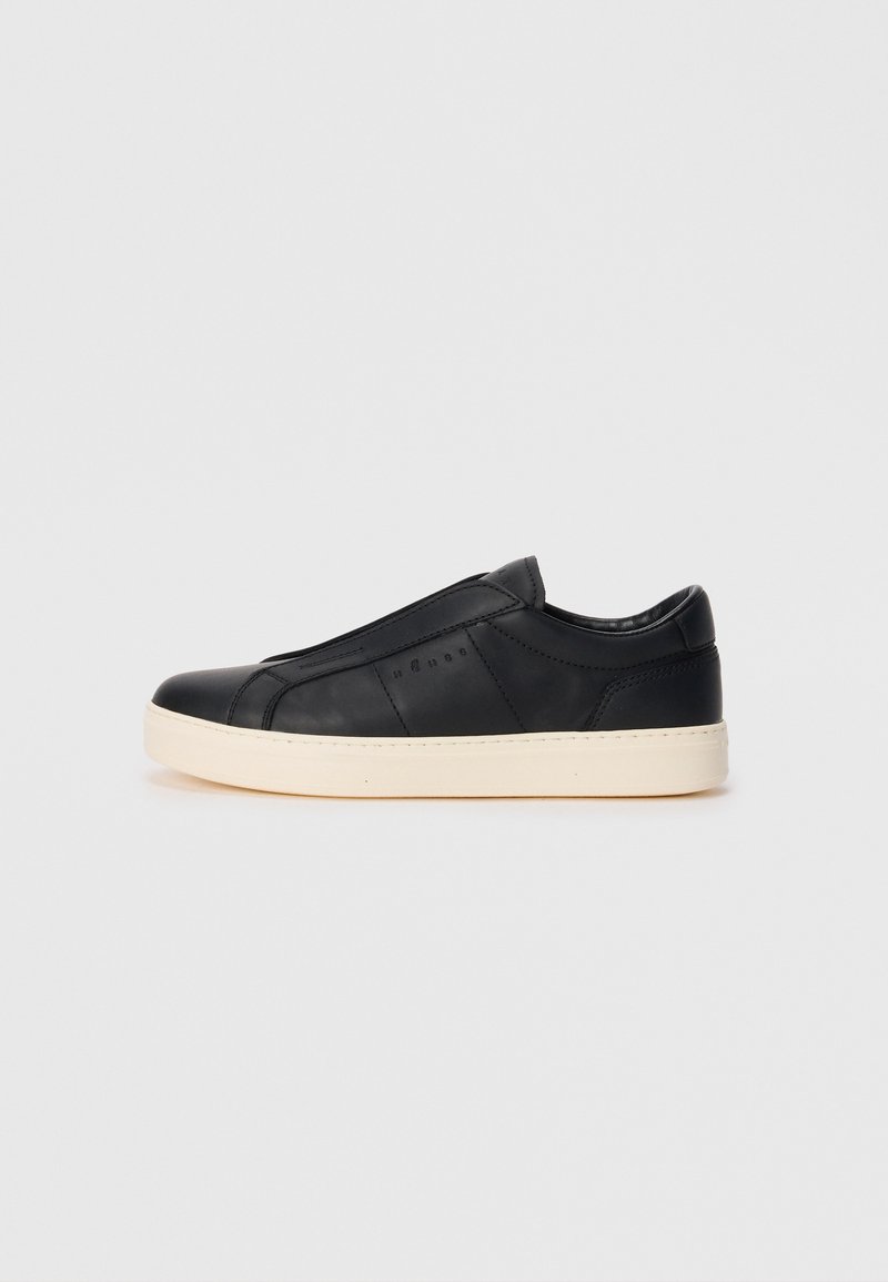 Must musta slip-on tennisebs musta viimistlusega, ümar toe ja beež outsole. Omab minimalistlikku disaini ja peeneid õmbluse accent.