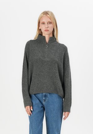 Gray, ribbed knit sweater with a high collar and half-zip closure. Features loose fit and long sleeves. Paired with blue denim jeans.