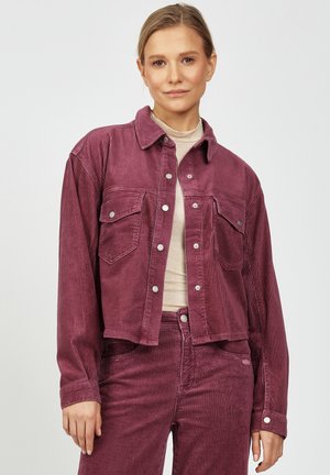 Corduroy jacket in deep plum with a collared neck, long sleeves, two chest pockets, and silver snap buttons. Textured fabric with ribbed pattern.