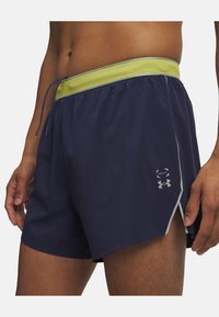 Navy blue athletic shorts with a lime green elastic waistband, featuring a logo, side slits, and a lightweight, smooth fabric texture.